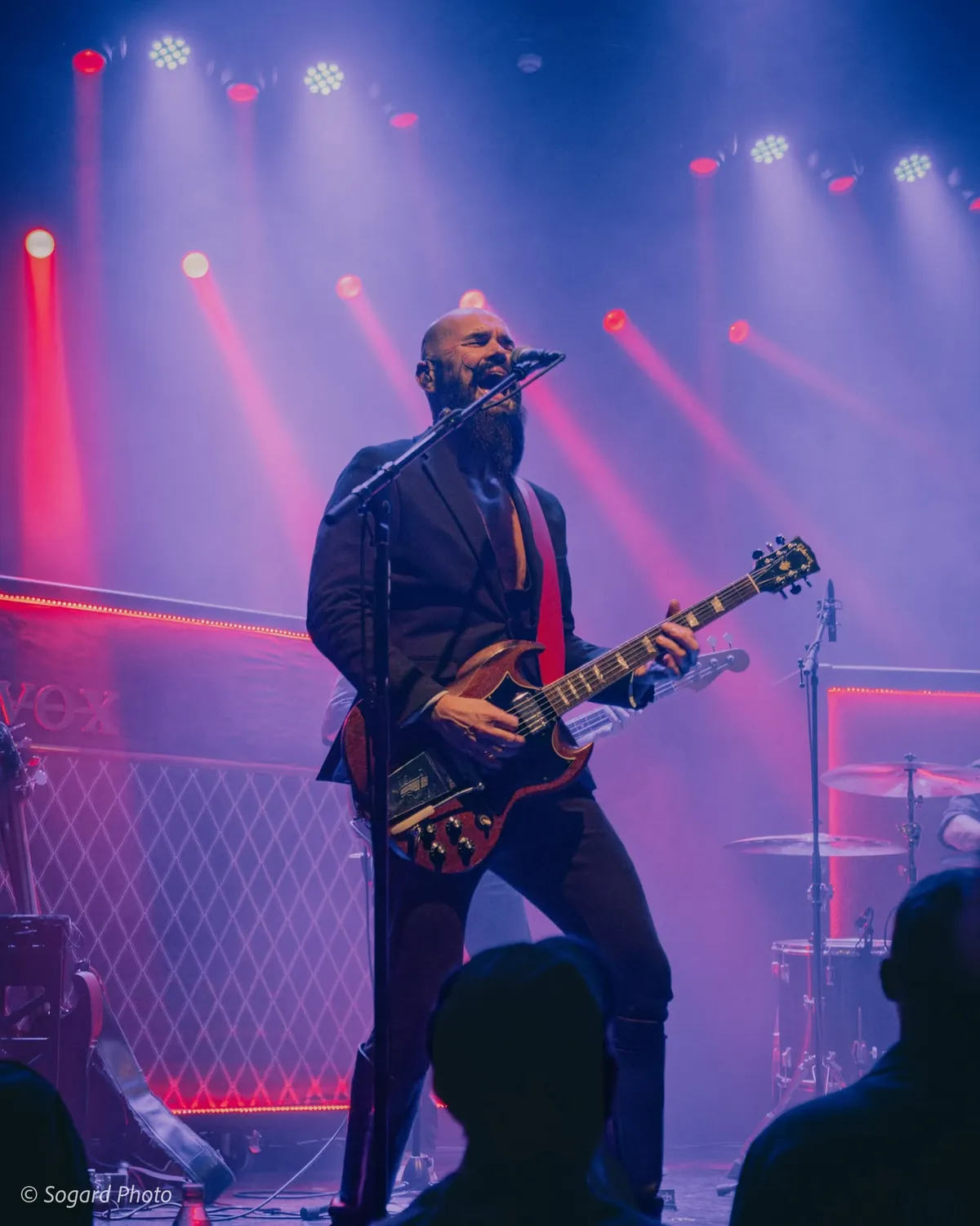 Koncertfotografi: guitarist på scenen i rødt scenelys