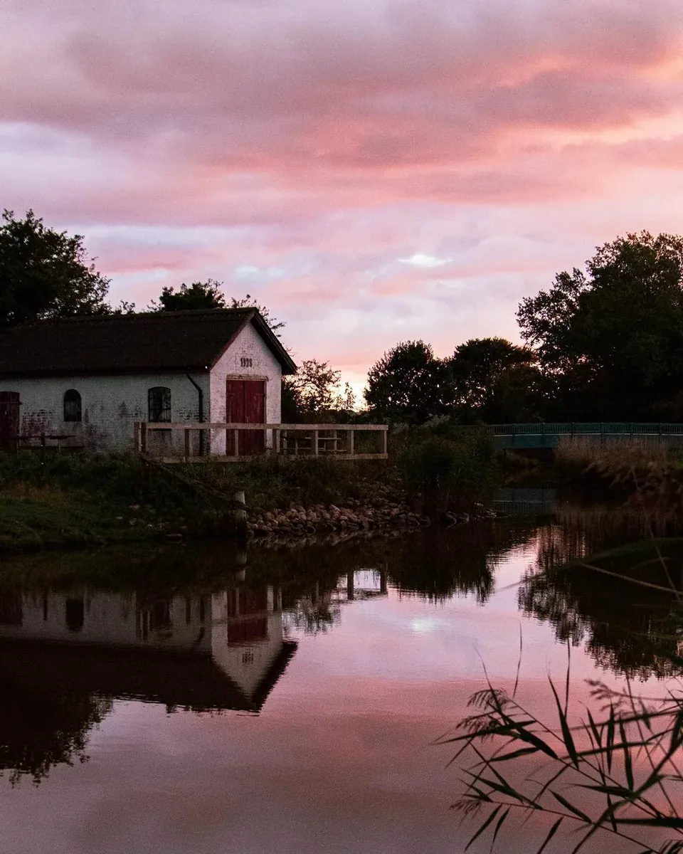 Hvidt hus ved s&oslash; i lyser&oslash;d solnedgang
