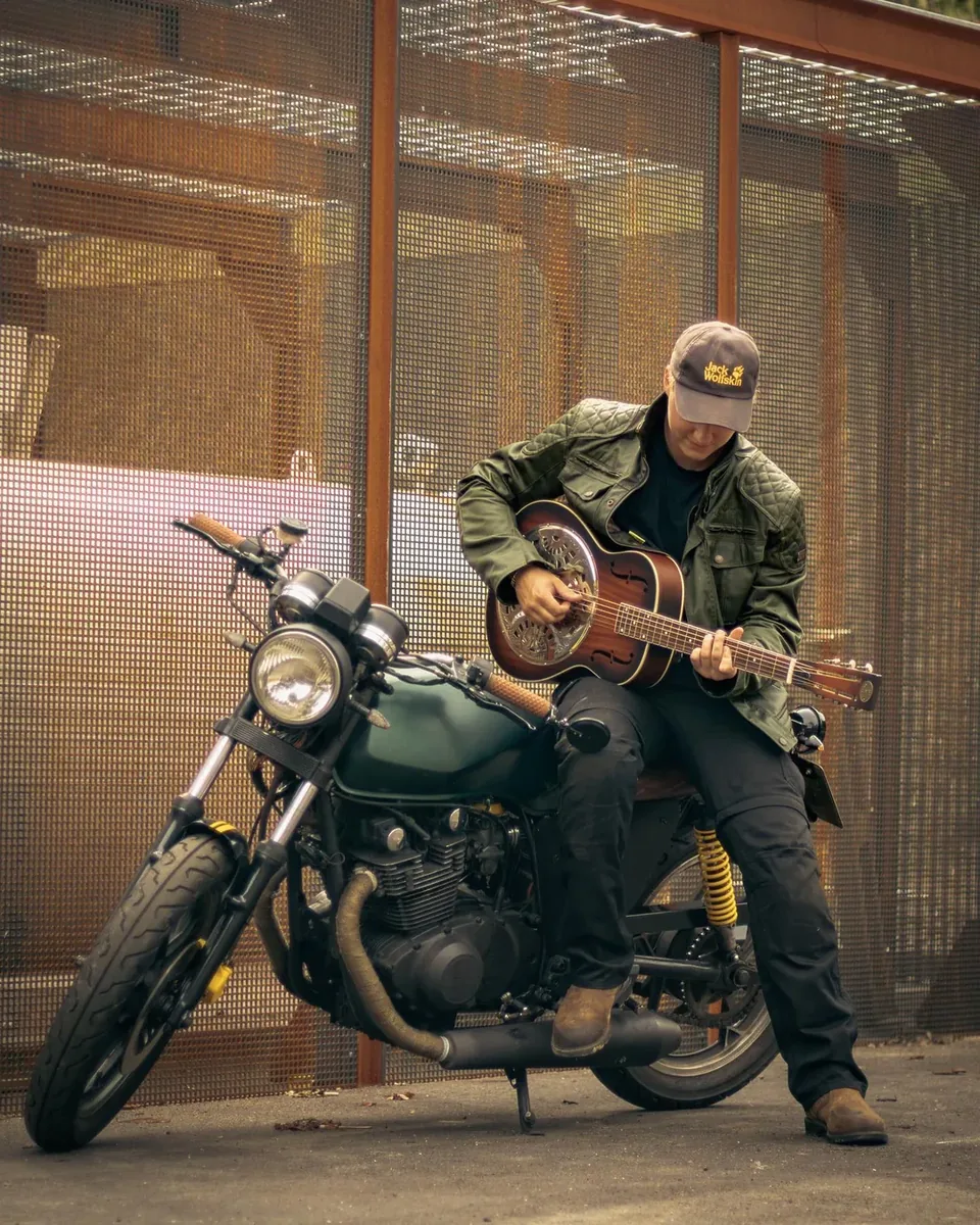 Musiker spiller resonatorguitar siddende p&aring; motorcykel